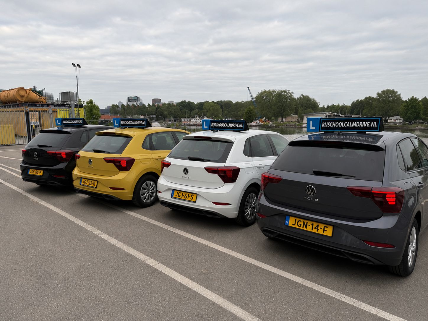 Vier lesauto's van Rijschool Calm Drive naast elkaar, elk met L-bord en dakbord